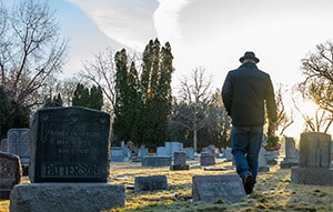Mann besucht Grab auf dem Friedhof